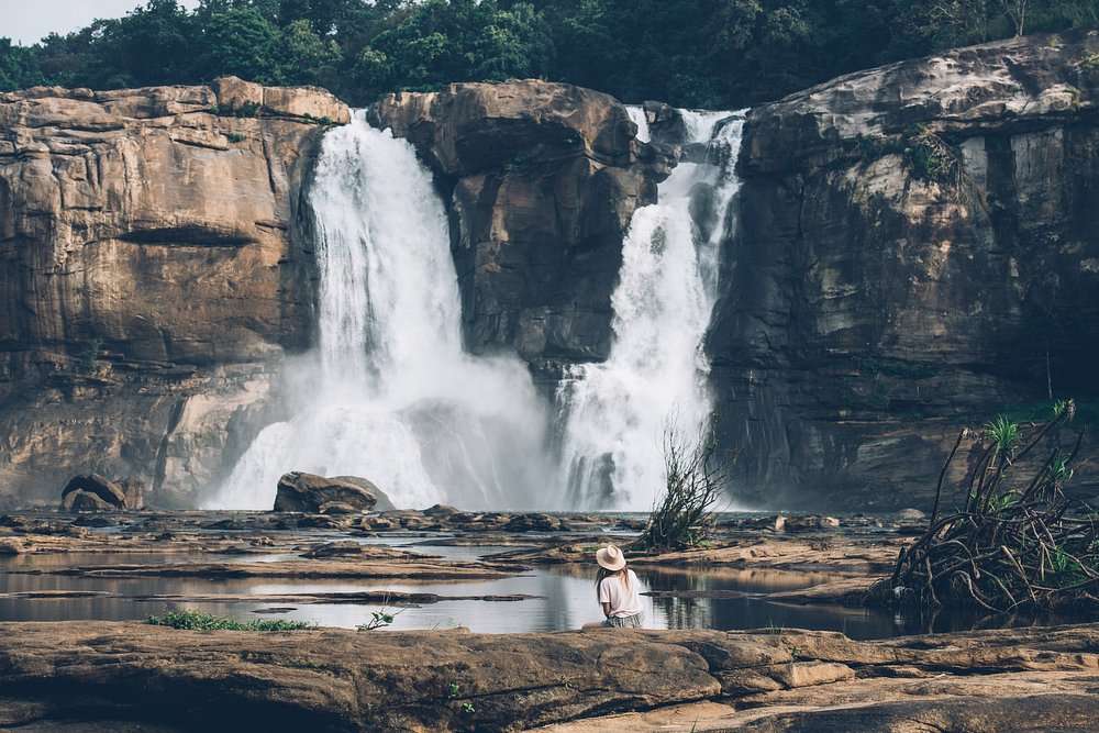Calm tourist sitting near Athirappilly Falls in Kerala enjoying natural serenity