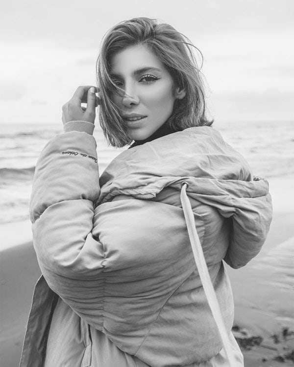 Stylish woman in winter coat posing on beach