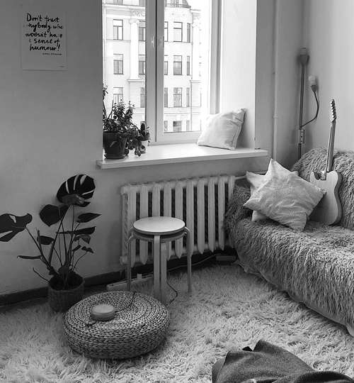 Stylish urban apartment with cozy corner seating, soft textures, indoor plants, and natural daylight from tall window